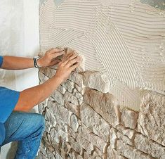 a man is working on a wall that has been made out of stone