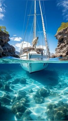 a sailboat floating in the ocean with rocks and water around it's edges