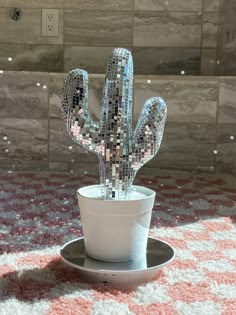 a glass cactus sitting on top of a saucer next to a tiled wall in a bathroom