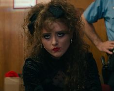 a woman with curly hair and blue eyes sitting in front of a man wearing a police uniform