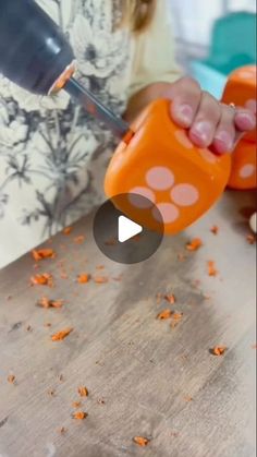 a person cutting carrots with a knife on top of a wooden table in front of them