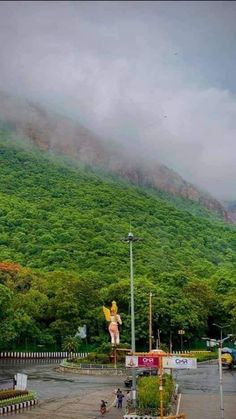 the mountains are covered in green vegetation and clouds above it, as people walk around