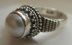 "Bali Suarti sterling silver and pearl ring. Small and beautiful, this ring has a soft iridescent white pearl, set in a raised bezel. The slightly domed pearl is encased in two rows of fine granulation pebbles and two rows of fine braiding. The sides have a striped-pebble vertical design. The back of the setting is solid and the band is thick. Beautifully made in the Balinese tradition and in excellent vintage condition. Please see detailed measurements below. > Size 5.5. *Thank you for doubl Silver Sterling Silver Pearl Ring, Hallmarked Sterling Silver Pearl Ring, Handmade Silver Pearl Ring For Formal Occasions, Handmade Vintage Pearl Ring In Sterling Silver, Unique Sterling Silver Pearl Ring In Silver, Unique Sterling Silver Pearl Ring, Handmade Vintage Sterling Silver Pearl Ring, Silver Rings With Pearl Drop, Handmade Classic Silver Pearl Ring