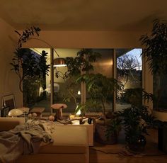 a living room filled with lots of plants next to a large glass window covered in sunlight