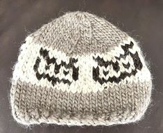 a knitted hat with black and white designs on the front, sitting on top of a table