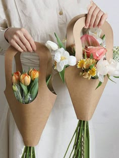 two bouquets are wrapped in brown paper and have flowers on each side, while someone is holding one