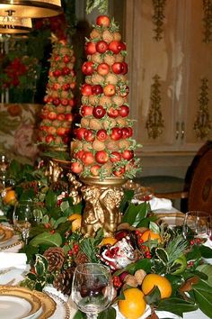 an elaborately decorated table with fruit and greenery on it, including oranges