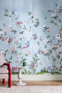 a chair and table in front of a floral wallpapered room with blue walls