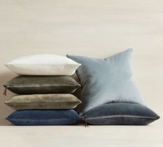 four pillows stacked on top of each other in different colors and sizes, all with zippered closures