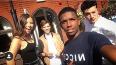 three young people standing in front of a brick building