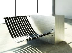 a bench sitting on top of a cement floor next to a wall and window sill