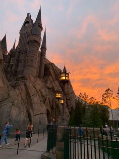 people are walking around in front of hogwart's castle at sunset or dawn