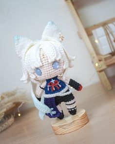 a crocheted doll is standing on a wooden stand