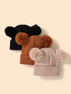 three hats with pom - poms hanging from the top, one brown and one black