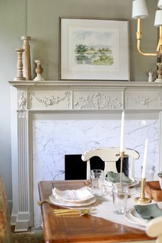 a dining room table is set with place settings and candles in front of the fireplace