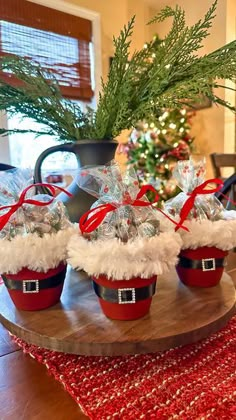 small baskets filled with candy sitting on top of a wooden tray next to a christmas tree