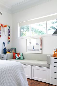 a bedroom with white walls and wooden flooring is pictured in this image, there are toys on the dressers