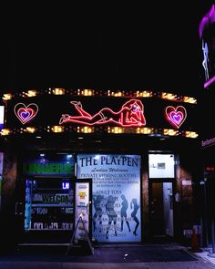 the front of a theater with neon signs and lights on it's sides at night