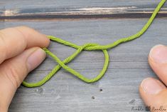 two hands are working on a piece of green string