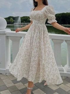 a woman in a white dress standing on a bridge with her hands out to the side