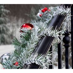 a christmas wreath is hanging on the banisters outside in front of snow covered trees