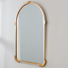 a mirror hanging on the wall next to a white wall with a gold trim around it