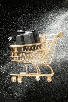 a gold shopping cart splashing with water on it and a black gift bag in the back