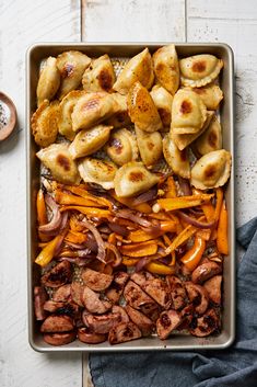 a pan filled with meat and veggies on top of a white wooden table