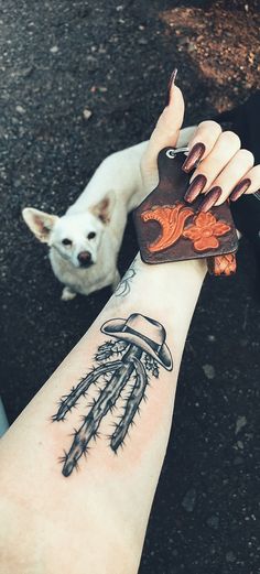 a person with a small tattoo on their arm holding a dog's paw and looking at the camera