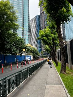 a person walking down a sidewalk in front of tall buildings with trees on both sides