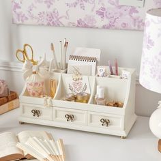 a desk with an open book, pen holder and other office supplies on top of it