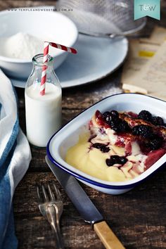 a bowl of fruit and yogurt with a bottle of milk next to it