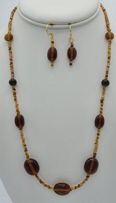 This simple brown beaded necklace was made with brown seed beads and round oblong brown glass beads.  The 22 inch necklace has a 14 K gold plated lobster claw clasp.  The matching earrings are made from the same brown beads as the necklace .  The earrings hang a total of 1 1/2 inches in length and have a 14 K gold plated earring wire. Elegant Brown Polished Beaded Necklace, Elegant Brown Beaded Necklace With Polished Beads, Elegant Brown Polished Beads, Brown Beaded Necklaces With Oval Beads, Brown Beaded Necklace With Oval Beads, Adjustable Brown Beaded Costume Jewelry Necklace, Brown Beaded Necklace With Colorful Oval Beads, Adjustable Single Strand Brown Beads, Handmade Brown Czech Glass Beads