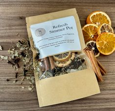 an orange and cinnamon spice mix in a bag next to some sliced oranges on a wooden table