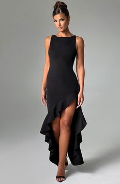 a woman is wearing a black dress with high slits on the side and an asymmetrical neckline