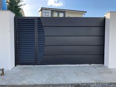 a modern gate is shown in front of a house with white walls and black shutters