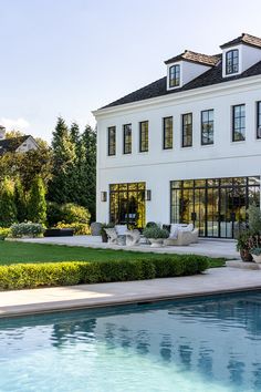 a large white house sitting next to a pool in front of a lush green yard