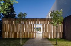 an entrance to a house with wooden slats on the wall and grass in front