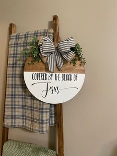 a wooden sign that says covered by the blood of jesus hanging on a wall next to a ladder