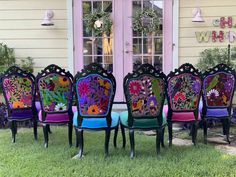 a group of colorful chairs sitting on top of a grass covered field next to a pink door