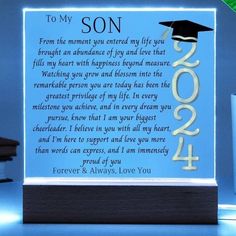 a light up plaque with the words to my son and graduation cap on it in front of a blue background