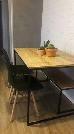 a wooden table with two black chairs next to it and a potted plant on top