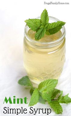 a mason jar filled with minty syrup on top of a white tablecloth next to a sprig of mint