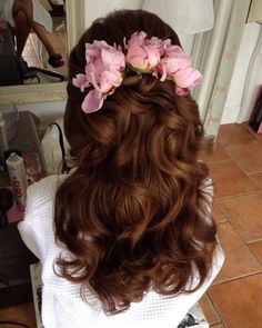 a woman with long brown hair and pink flowers in her hair is looking into the mirror