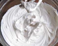 a glass bowl filled with whipped cream on top of a wooden table