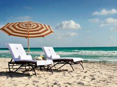 two lounge chairs and an umbrella on the beach