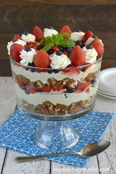 a dessert with strawberries, blueberries and cream in a glass dish on a table