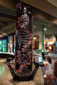 there is a child playing with a computer in a museum display case that looks like a christmas tree