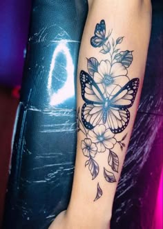 a woman's arm with a butterfly and flower tattoo on the left side of her arm