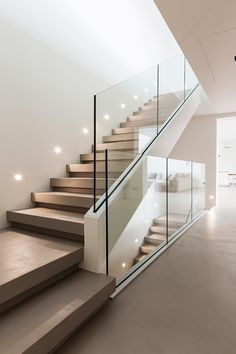 there is a stair case with glass railings on the top and bottom floors in this modern house